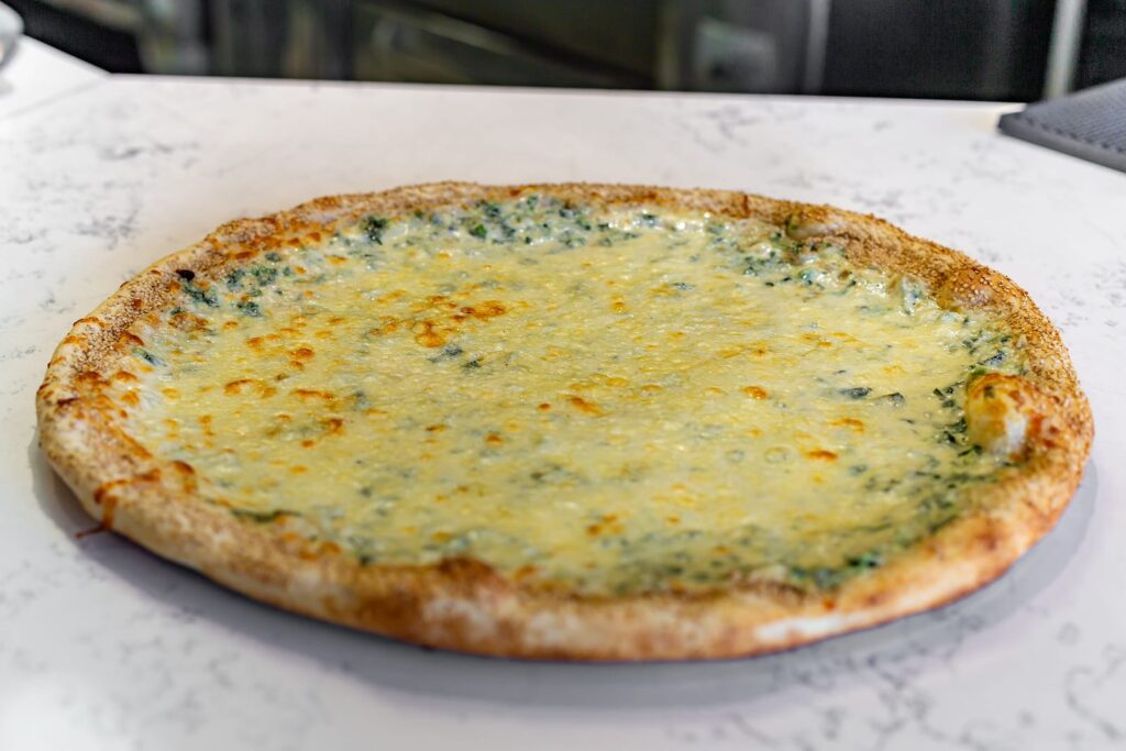 Chefs Spinach Pizza: spinach and melted mozzarella in a white cream sauce on a sesame-crusted pie