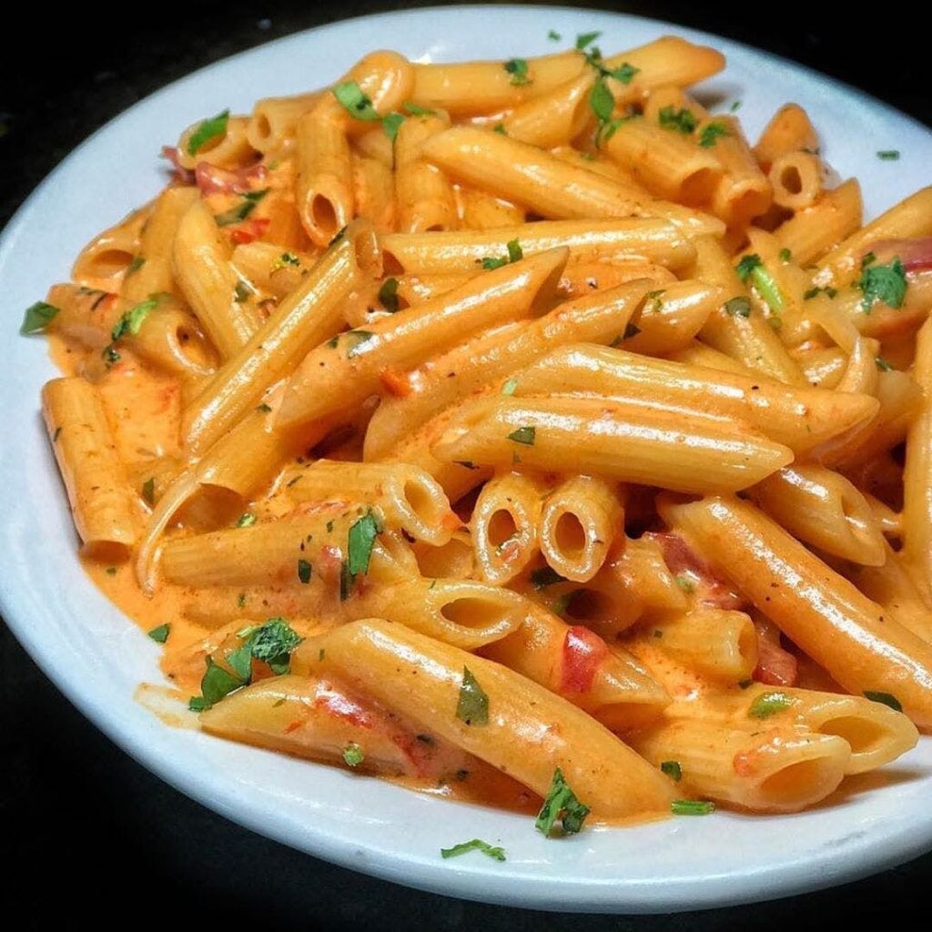 Penne alla vodka in a creamy pink sauce with prosciutto and chopped parsley