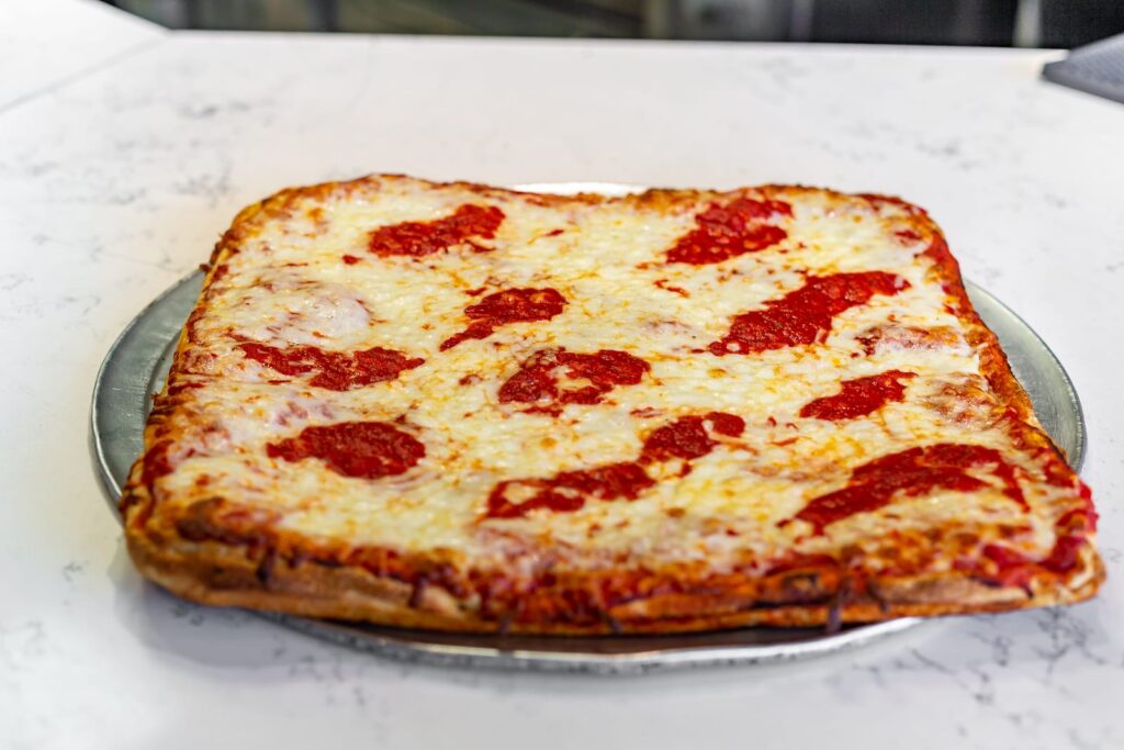 A square Sicilian pie with a thick crust, mozzarella and spoonfuls of tomato sauce